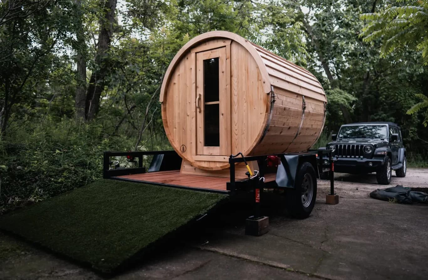 A mobile barrel sauna mounted on a trailer
